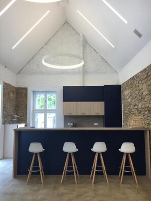 Eine Küche mit Steinwand, einer Bar mit Hockern und einem Oberlicht.