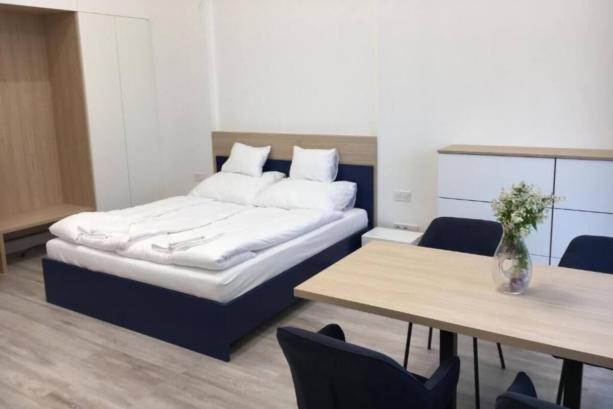 A modern hotel room with a bed, a desk, and a chair.