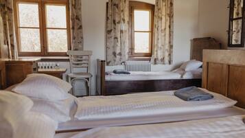 A room with two beds, a radiator, a wooden cabinet, and a window with curtains.