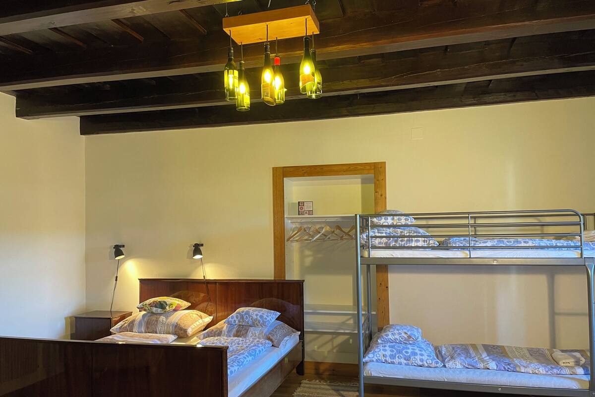 A room with a bunk bed, a wooden headboard, a bedside table with a lamp, and a hanging light fixture.