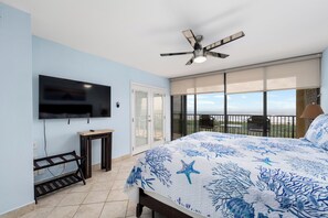 A bedroom with a bed, a ceiling fan, a TV mounted on the wall, a sliding glass door leading to a balcony, and a view of the ocean. - Beachfront Sea Vista condo with wraparound Gulf-view balcony + $75 beach gear rental credit (South Padre Island)