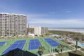 A beachfront hotel with multiple tennis courts, a pool, and a view of the ocean. - Spacious beachfront corner condo with Gulf views, 3 pools & hot tubs! (South Padre Island)