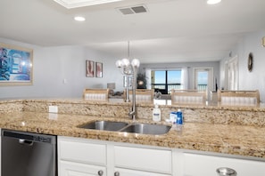 A kitchen with granite countertops, stainless steel sink, and white cabinetry. - Spacious beachfront corner condo with Gulf views, 3 pools & hot tubs! (South Padre Island)