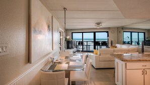 Ett modernt kök med matplats, en vit soffa och utsikt över havet.