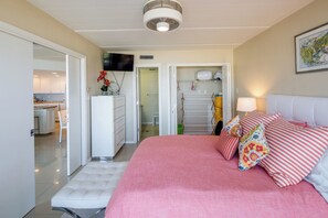 Ein Schlafzimmer mit Bett, Fernseher, Kleiderschrank und einem durchgegangenen Tür sichtbaren Badezimmer.