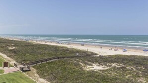 Ein Strand mit einem hölzernen Promenadenweg, Sandstrand und Meerblick.