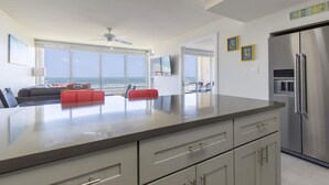 Eine moderne Küche mit einer großen Kochinsel, einem Edelstahl-Kühlschrank und Blick auf den Strand.