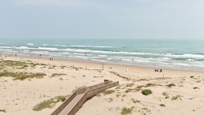 A beach with a wooden boardwalk, sandy dunes, and the ocean. - Fourth-floor Sea Vista condo with Gulf sunrises, pools, hot tubs + $75 beach gear rental credit (South Padre Island)