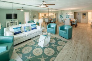 A spacious living room with teal and white furniture, a glass coffee table, and a star-patterned rug. - Oceanfront Saida IV corner condo with Gulf views, pools + $75 beach gear rental credit (South Padre Island)