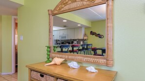 Ein Zimmer mit einem Holzkonsolentisch, Korbwannen, einem Spiegel und einer Küchenzeile im Hintergrund.