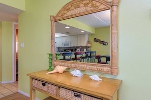 Ein Zimmer mit einem Holzkonsolentisch, Korbwannen, einem Spiegel und einer Küchenzeile im Hintergrund.