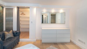 Un dormitorio moderno con cama, cómoda, espejo y armario.
