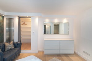 A modern bedroom with a bed, a dresser, a mirror, and a closet. - Modern Split-Level flat, South Kensington, London - Pass the Keys (London)