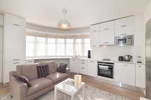 A modern kitchen with white cabinetry, a microwave, and a coffee maker. - Modern Split-Level flat, South Kensington, London - Pass the Keys (London)