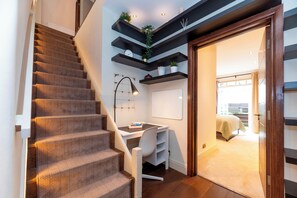 A staircase with patterned carpet, a desk with a chair, and shelves with plants. - Luxury Family Home with Garden in West Kensington - 2 Mins to Tube - Pass the Keys (Londonderry)