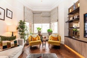 A living room with a sofa, two armchairs, a coffee table, a lamp, and a TV. - Luxury Family Home with Garden in West Kensington - 2 Mins to Tube - Pass the Keys (Londonderry)