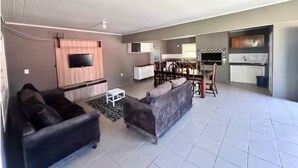 A living room with a sofa, a TV, and a dining area with chairs.