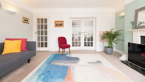 A living room with a sofa, red chair, TV, and a large window. - Riverside Serenity near Kingston and Hampton Court - Pass the Keys (Surbiton)