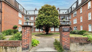 A courtyard with a large tree, brick buildings, and a sign reading 'Westfield Court.' - Riverside Serenity near Kingston and Hampton Court - Pass the Keys (Surbiton)
