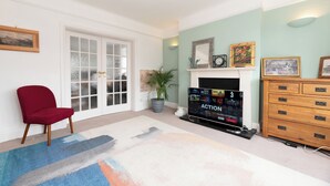A room with a red chair, a fireplace, a television, and a wooden dresser. - Riverside Serenity near Kingston and Hampton Court - Pass the Keys (Surbiton)