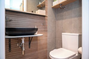 A bathroom with a modern sink, a toilet, and wooden paneling. - The Ivory Suite- Stylish Central Croydon Apartment - Pass the Keys (Croydon)