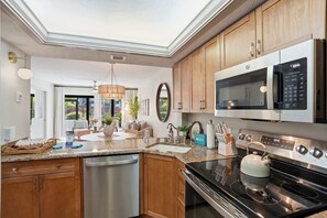 A modern kitchen with wooden cabinets, stainless steel appliances, and a granite countertop. - B-115 - Totally Updated - First Floor- Sleeps 6 (Naples)