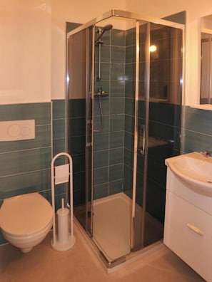 Ein Badezimmer mit Duschkabine, Toilette und Waschbecken.