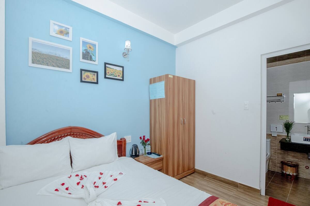 Un dormitorio con cama, armario, mesita de noche y un cuadro con marcos en la pared.
