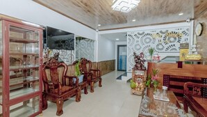 Uma área de recepção com um balcão de madeira, uma vitrine de vidro e uma parede com padrão decorativo.