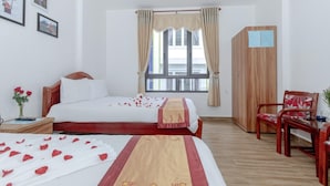 Quarto de hotel com cama, mesa de cabeceira, cadeira, guarda-roupa e janela com cortinas.
