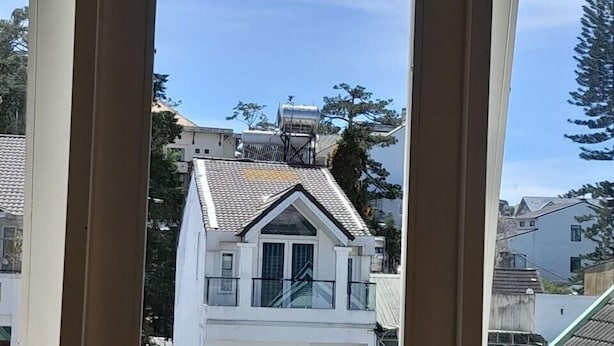 Uma casa branca com placa indicando que foi construída em 1995, telhado de telhas e varanda.