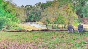 A river flowing through a forest with two chairs facing the water. - River`s Edge Retreat (McComb)