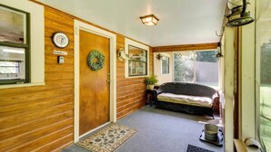 A wooden interior with a door, a wreath, a wicker sofa, a small table, and a window. - River`s Edge Retreat (McComb)