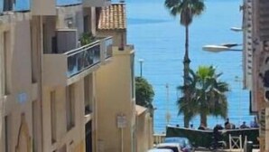 A street with parked cars and buildings, a clear sky, and a view of the sea. - Renovated 2-room apartment 30 m from the beach - Le Mourillon (Toulon)