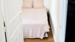 A narrow room with a bed, a hanging light fixture, and a television on the wall. - Renovated 2-room apartment 30 m from the beach - Le Mourillon (Toulon)