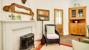 A room with a fireplace, a mounted deer head, a chair, a cabinet, and a door.