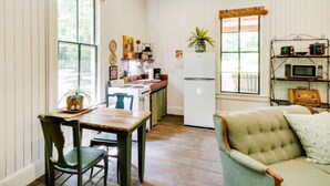 A compact kitchen with a dining table, chairs, a refrigerator, and a microwave.