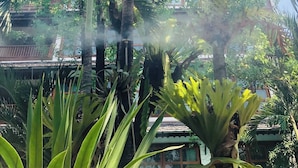 Un giardino tropicale con palme e un edificio tradizionale sullo sfondo.