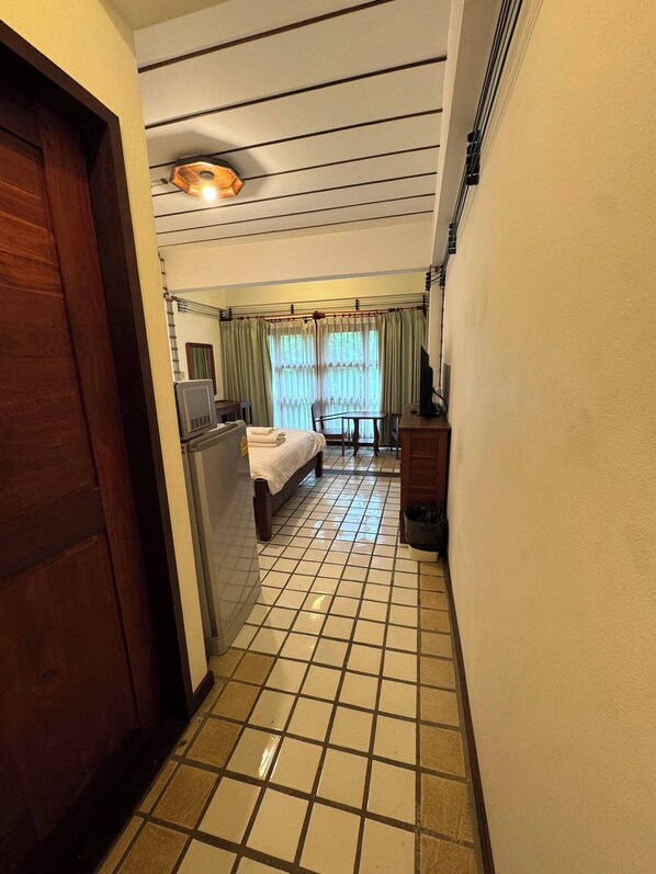 A hotel room with a bed, a desk, a chair, a TV, and a window with curtains.