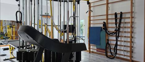 Une salle de sport équipée de matériel d’exercice, d’un tapis de course et d’un support mural pour les élastiques de résistance.