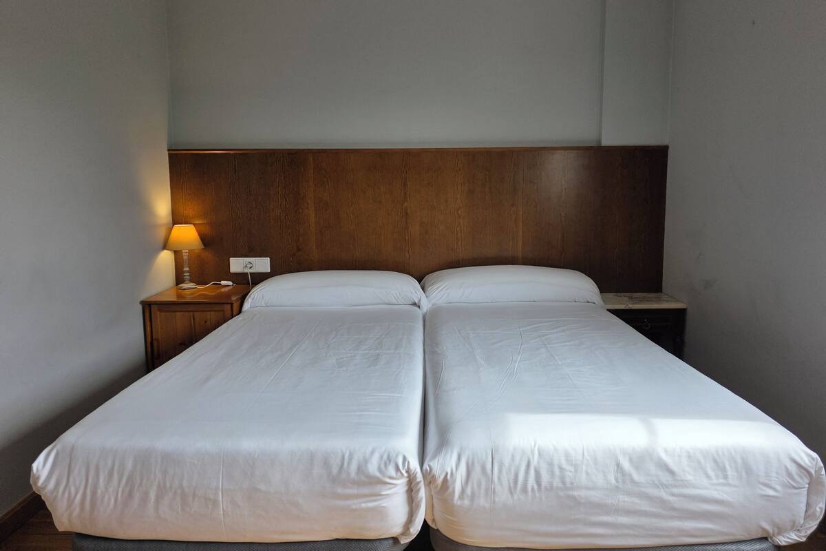 En dobbeltseng med hvide sengetøj på et hotelværelse.