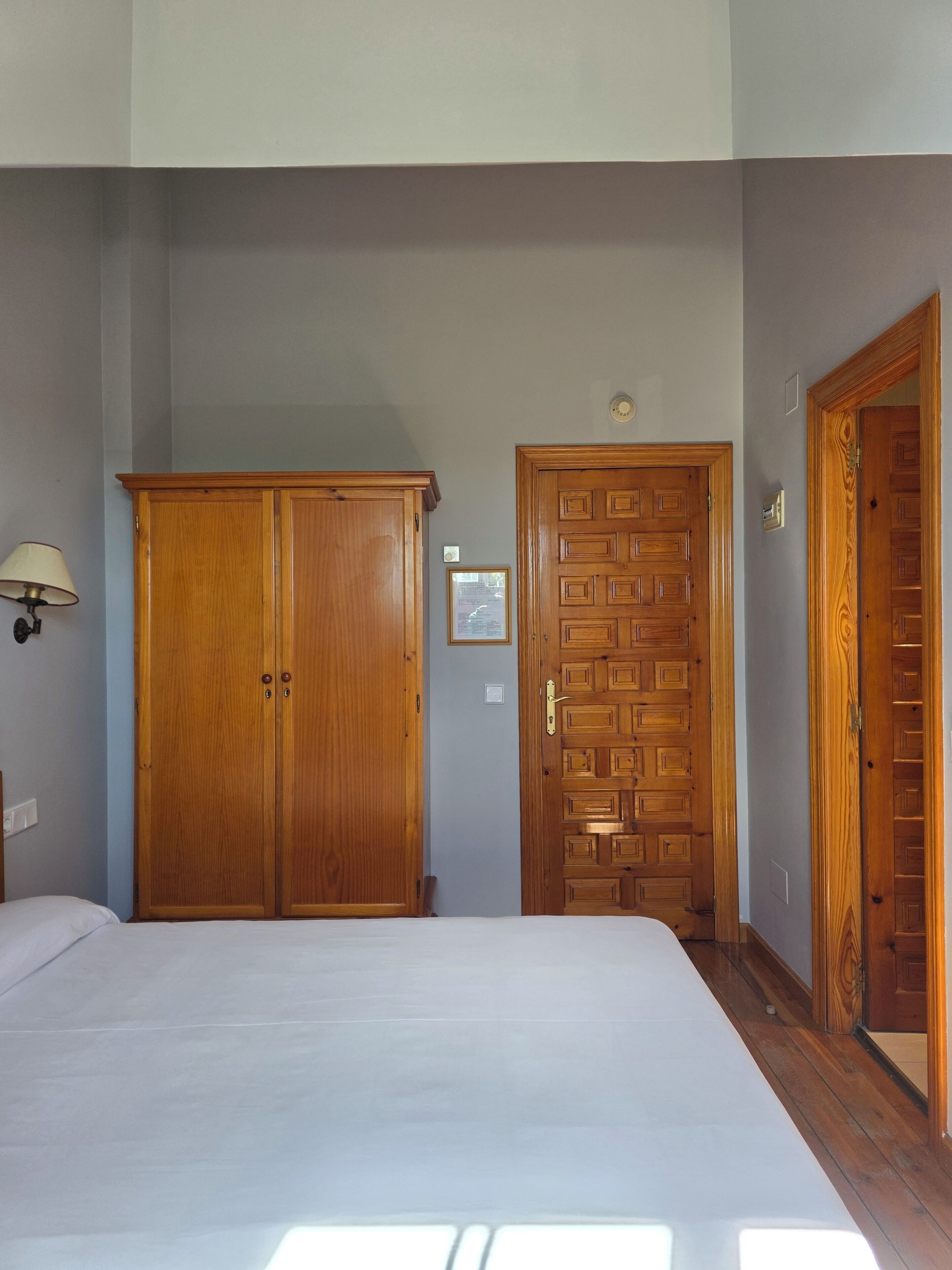 A bedroom with a bed, a wardrobe, and a door.
