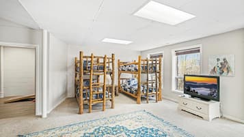 Ein Zimmer mit Etagenbetten, einem Fernseher, einem Gemälde und einem Fenster.