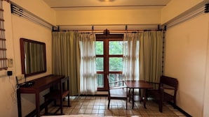 A hotel room with a bed, a desk, a chair, a table, and a window with curtains. - Room-302 Serene Teak Boutique Apartments (Chiang Mai)