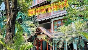 A two-story building with a swimming pool, surrounded by tropical plants and a 'Merry Christmas & Happy New Year' banner. - Room-302 Serene Teak Boutique Apartments (Chiang Mai)