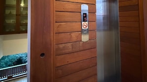 A wooden elevator door with a digital display and a no-smoking sign. - Room-302 Serene Teak Boutique Apartments (Chiang Mai)
