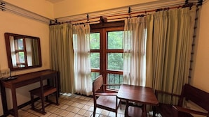 A room with a wooden desk, chair, and table, a window with curtains, and a mirror on the wall. - Room-302 Serene Teak Boutique Apartments (Chiang Mai)