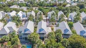 Zona residencial con varias casas de techo a dos aguas, rodeada de palmeras.