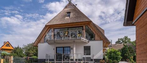 Un bâtiment à deux étages, doté d’un toit en pente, d’un balcon à l’étage supérieur et d’une cour dallée.