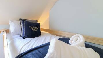 A bedroom with a bed, pillows, a blanket, and a towel.